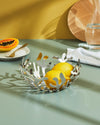 Silver-tone coral fruit holder by Alessi with organic cut-out design holding lemons on a table.