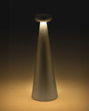 Conical matte gray table lamp by Alessi with a luminous mushroom-shaped top diffuser casting warm light.