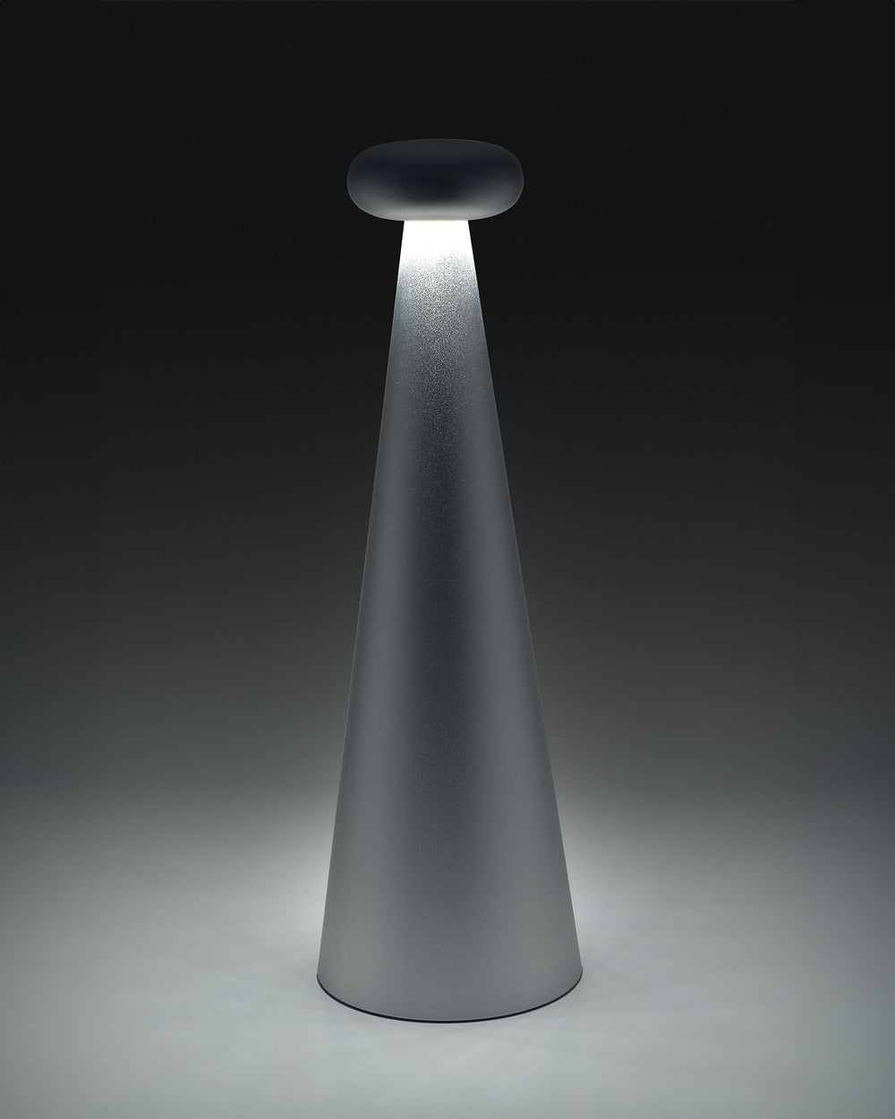 Gray conical Bedin lamp by Alessi, with a dark flat top emitting a bright downward light beam.