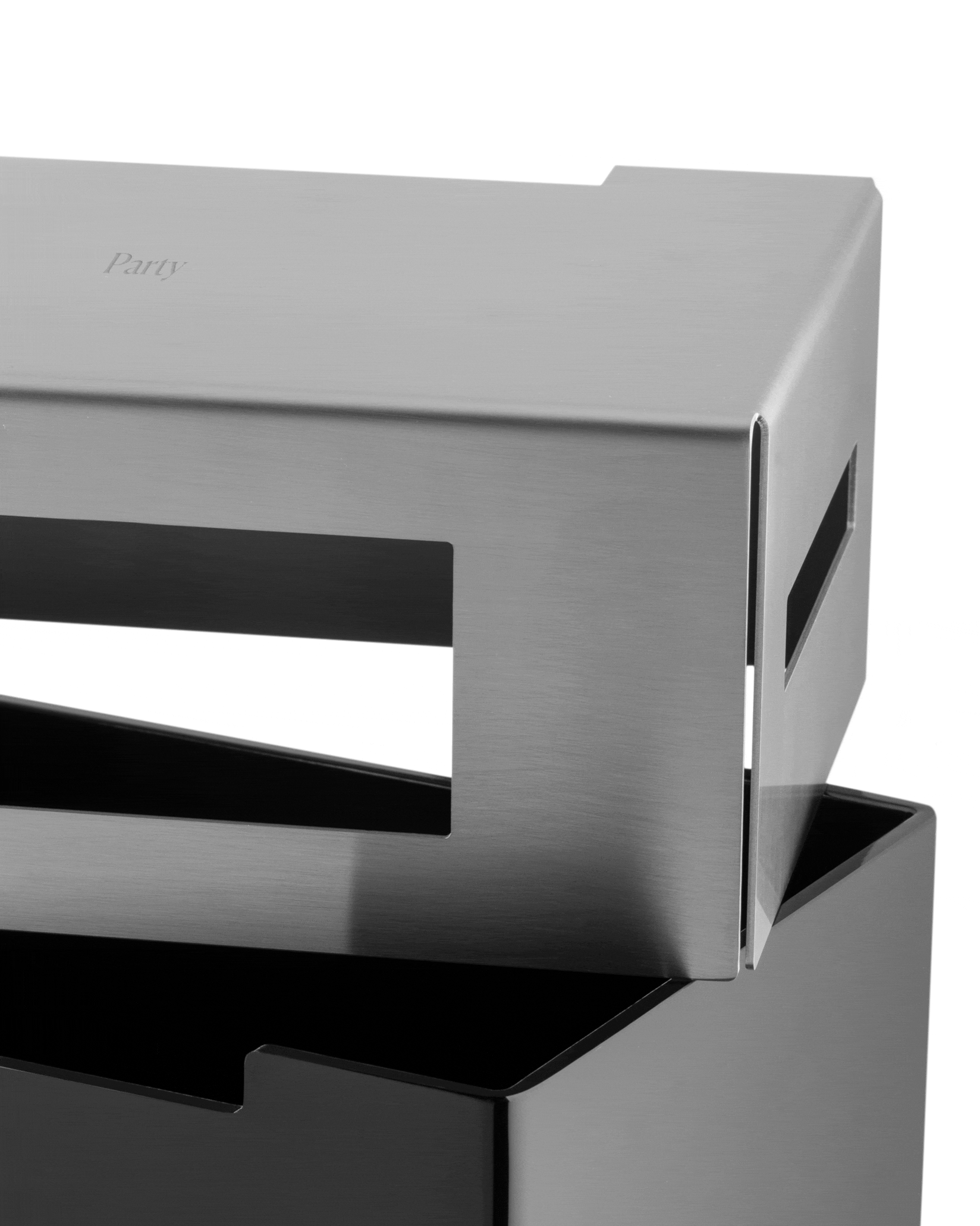 Brushed steel and black modular organizer by Alessi with 'Party' etched on the top panel and slotted sides, angled close-up.