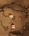 Orange square tiger Christmas tree ornament by Alessi, with black stripes and square ears, hanging from a bare branch.