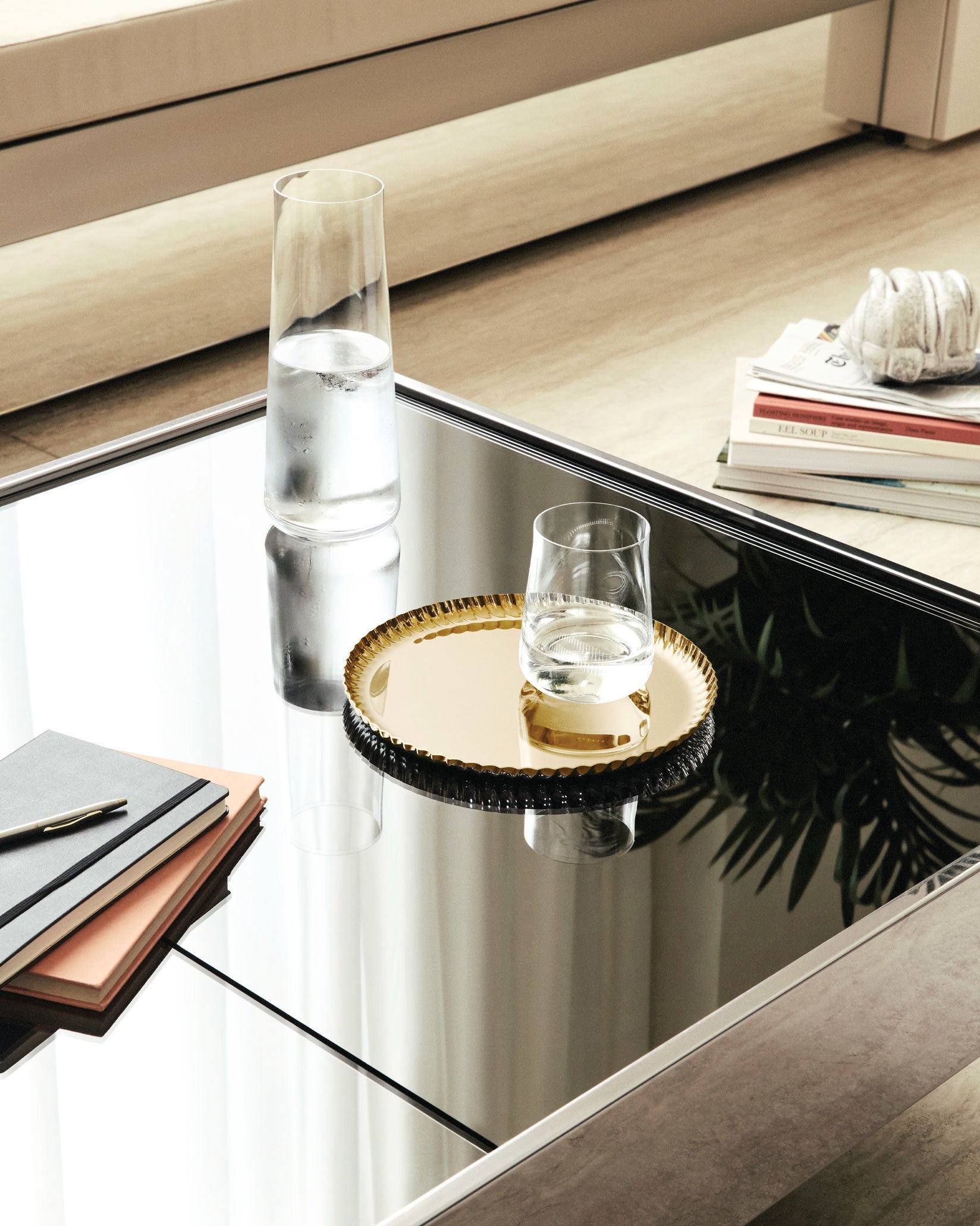 Gold round Pleats tray by Alessi, featuring a pleated edge, on a mirrored table.