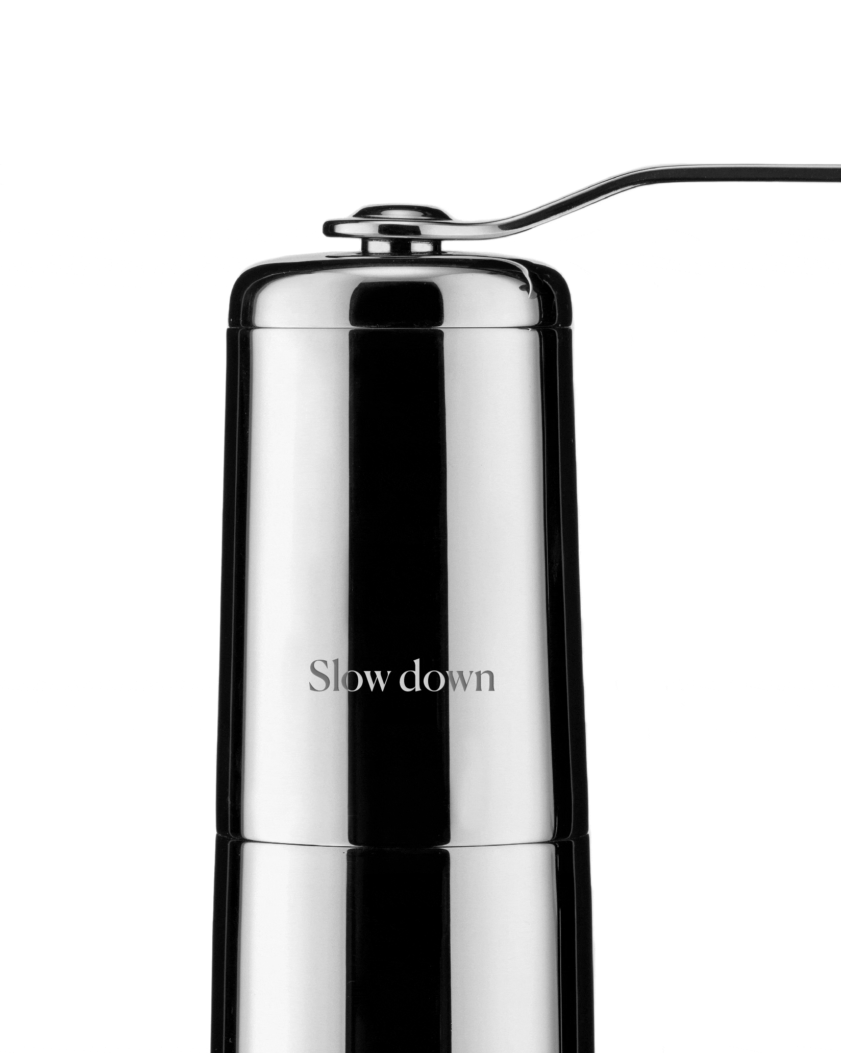Silver metal coffee grinder by Alessi, with a reflective surface, top handle, and "Slow down" text.