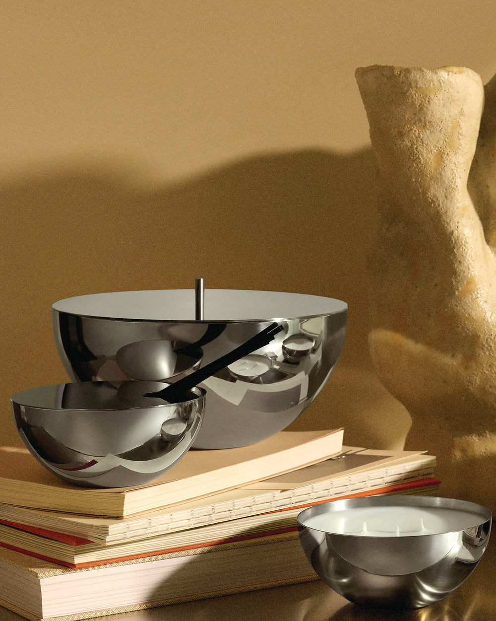 Stainless steel Rocc containers by Alessi, featuring a large lidded and smaller polished bowls on books.