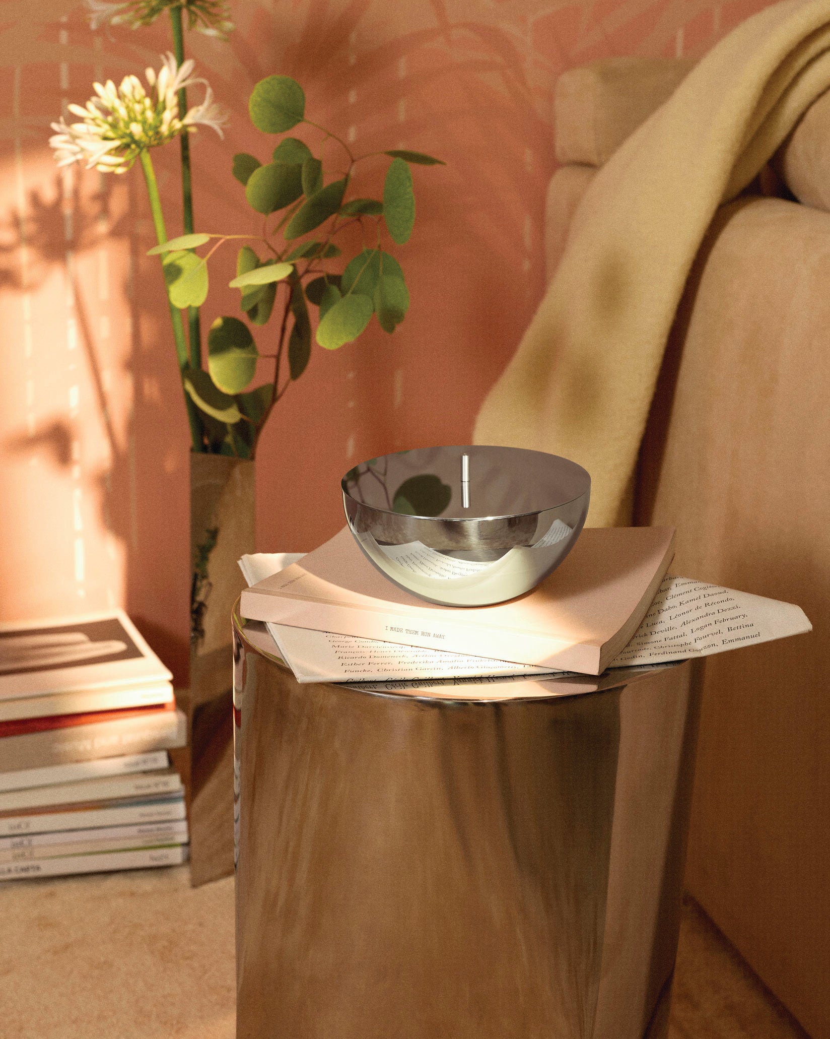 Polished chrome container by Alessi with a flat lid, reflecting a bright interior.