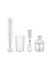 White hand blender by Alessi with a pleated design, displayed with clear measuring cup, whisk, and chopper attachments.