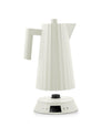 Off-white electric kettle by Alessi with a pleated texture, separated from its base featuring a digital control panel.