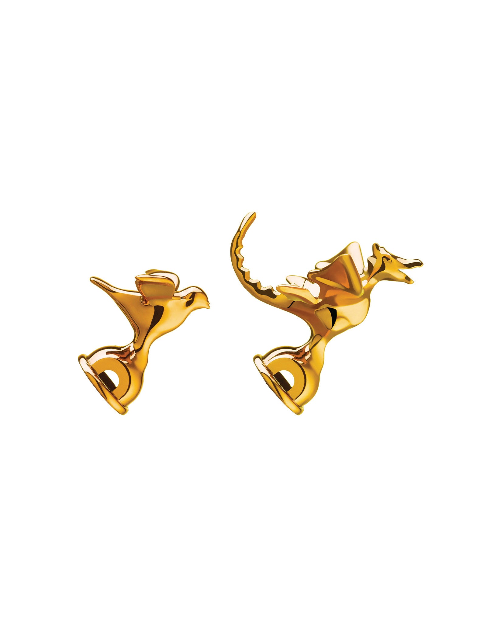 Golden stylized kettle whistles by Alessi, one bird-like and one dragon-like, with a high-shine metallic finish.