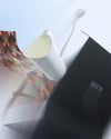 Tea gift set by Alessi with a white heart-shaped mug, a spoon, a black box, and geometric patterned paper.