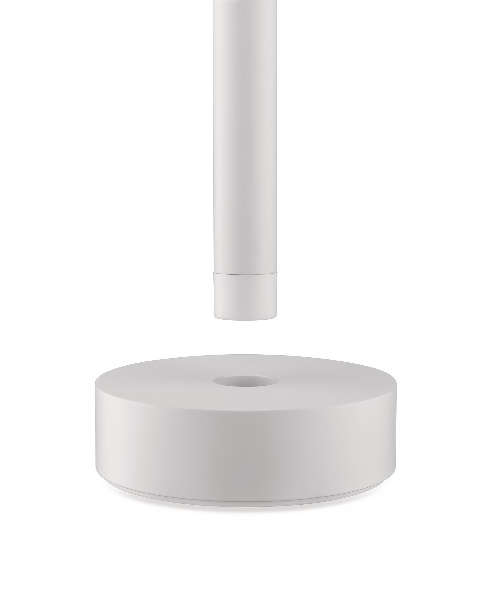 White Tsumiki lamp by Alessi, featuring a cylindrical part above a round base with a central opening.
