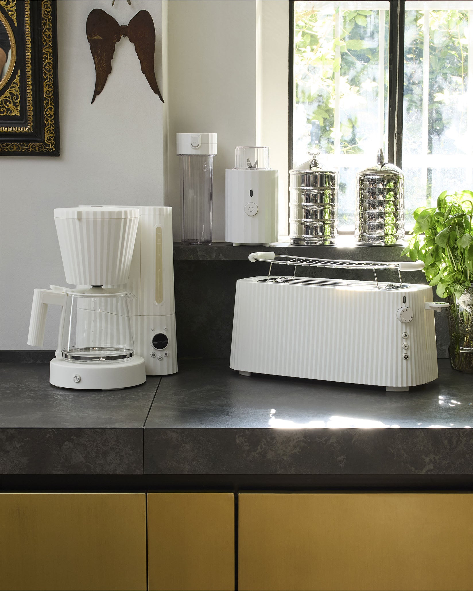 White ribbed toaster by Alessi with a chrome warming rack on a dark countertop in a kitchen.