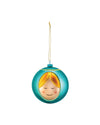 Teal round Madonna ornament by Alessi, with a smiling stylized face and golden hair, hanging from a gold chain.