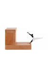 Light brown wooden desk accessory by Alessi, featuring a stylized silver and black metal figure leaping from a slot.