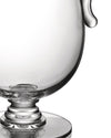 Transparent glass compote by Alessi with a ribbed stem and a pouring spout, cropped against white.