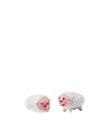 White ceramic sheep figurines by Alessi, one sleeping and one smiling, with rosy faces and textured bodies.
