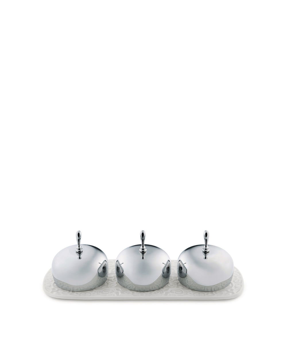 Shiny silver three-piece condiment set by Alessi with embossed container bases on a matching patterned white tray.