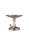 Silver and gold seal decorative stand by Alessi, balancing a golden sphere and a shallow bowl with red and white geometric patterns, on a matching base.