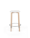 A white-seated bar stool with light wood legs by Alessi, featuring a curved silver-toned footrest.