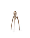 Bronze-toned metal citrus squeezer by Alessi, with a spiral top, three legs, and visible branding on one leg.