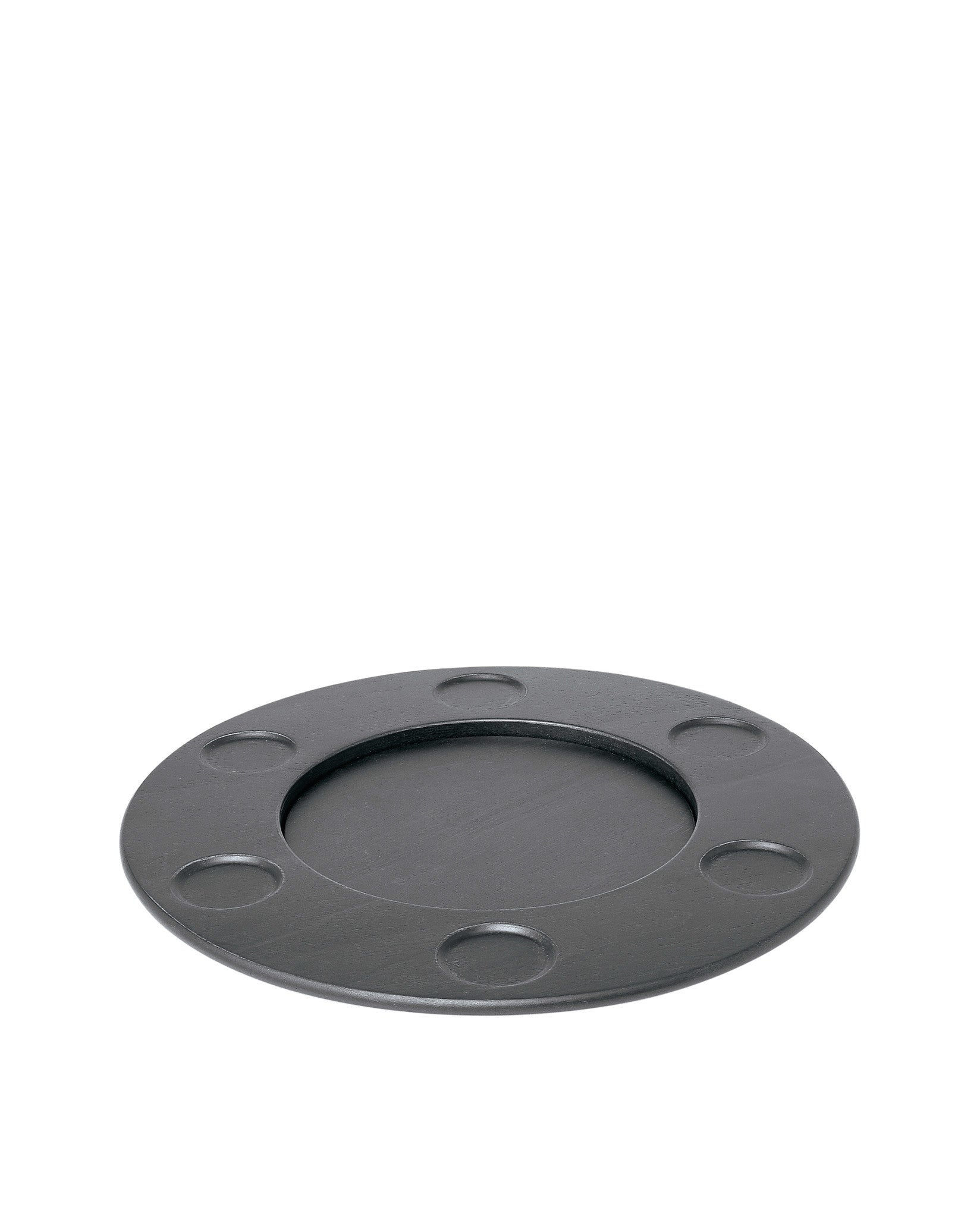 Round matte dark grey trivet by Alessi with a central well and seven smaller circular indentations.