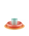 Colorful kids' tableware set by Alessi, with a light blue cup stacked in a coral bowl on an orange plate.