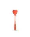 Large coral heart-shaped spoon by Alessi with a long handle, standing upright and casting a soft shadow.