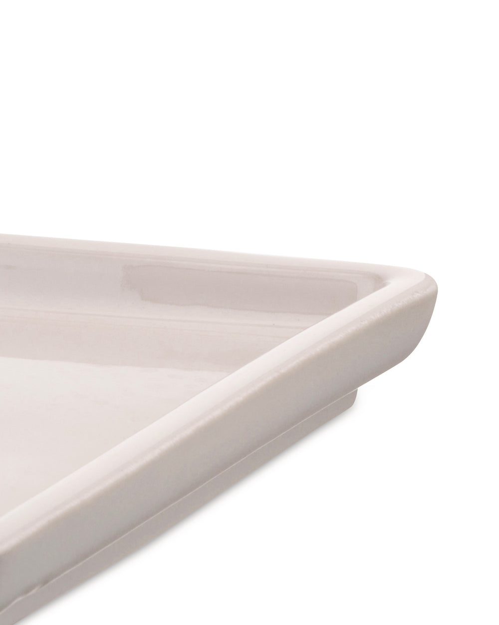 Light beige ceramic tray by Alessi, cropped close-up showing a corner and glossy finish.