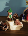 Ceramic shepherd figurine by Alessi with a green hat and staff, standing on a white base alongside pink ceramic sheep.