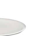 White plate by Alessi with a smooth, minimalist design, shown cropped from the bottom right.