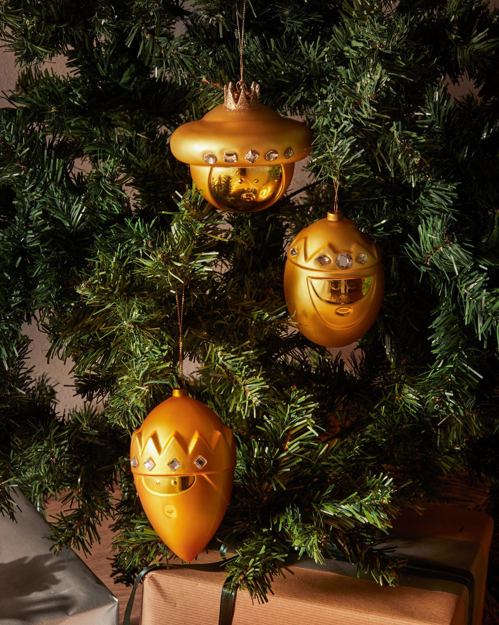Golden Baldassarre Christmas ornament by Alessi, featuring a character design with crown details and clear gem embellishments, on a Christmas tree.