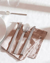 Sleek silver flatware place setting by Alessi, with fork, spoon, and knife on a linen napkin.