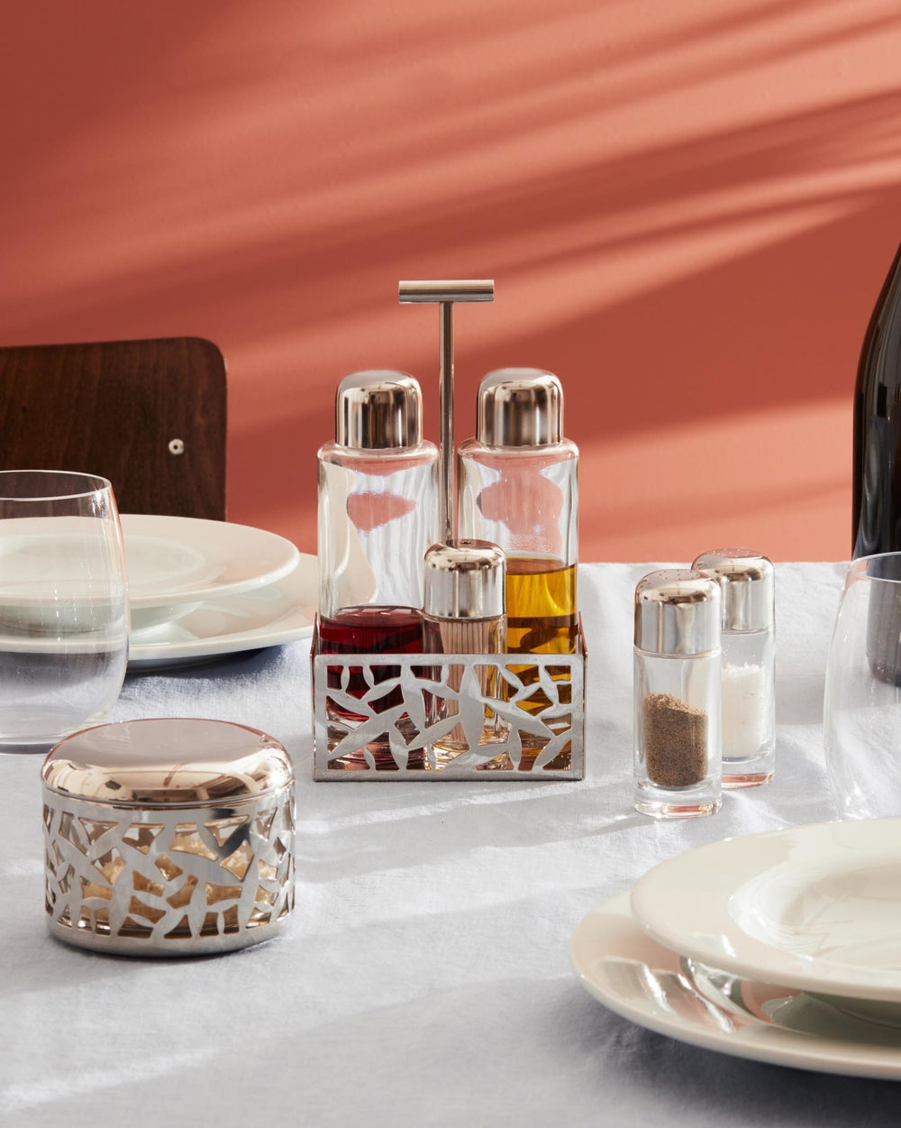 Silver metal oil cruet and condiment caddy by Alessi with a decorative 'CACTUS!' laser-cut design, holding glass bottles.