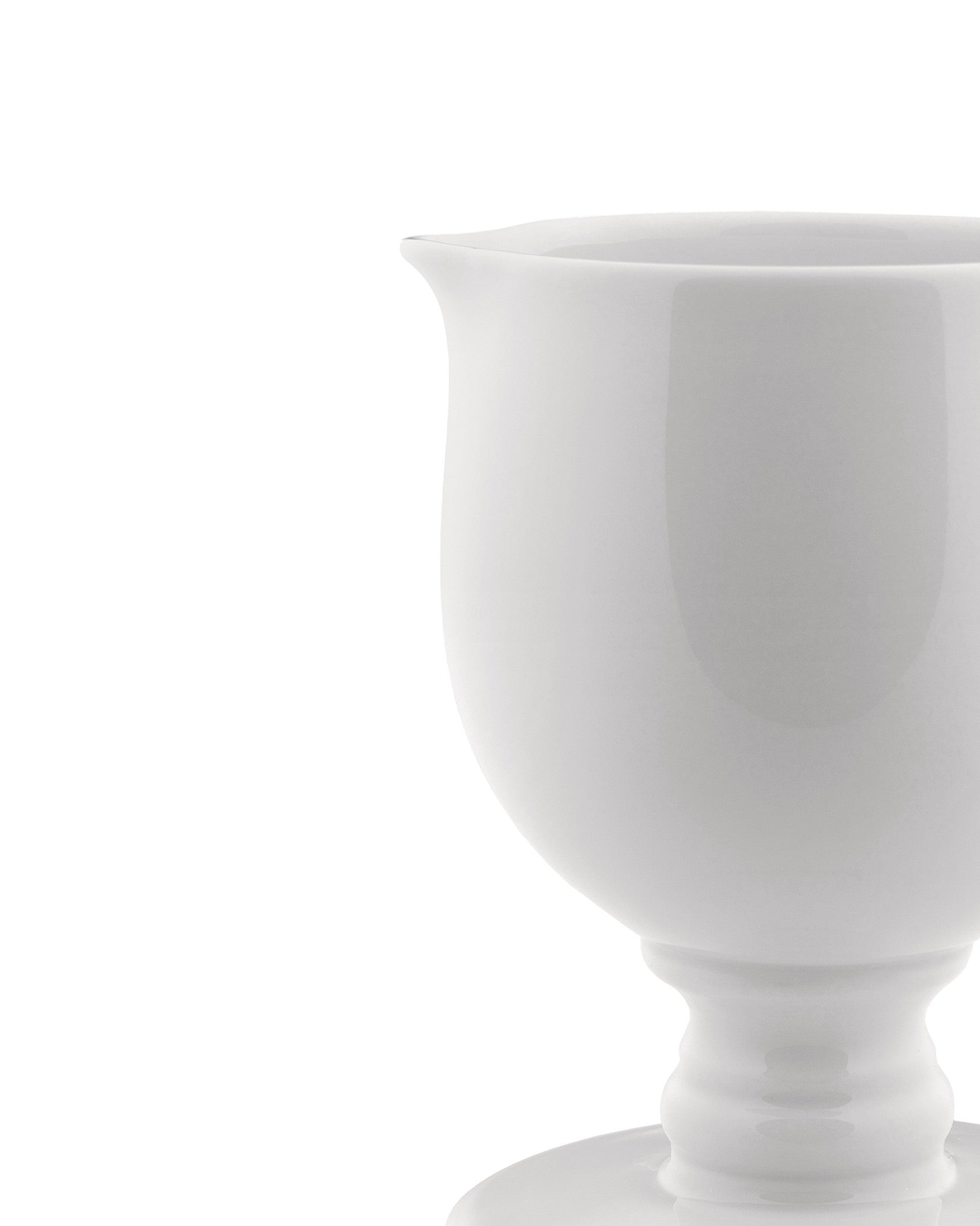 White ceramic creamer by Alessi, elegantly shaped with a footed base and subtle pouring spout, shown right-cropped.