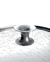 Silver metal pot lid by Alessi, featuring an etched wavy pattern and a scalloped handle.