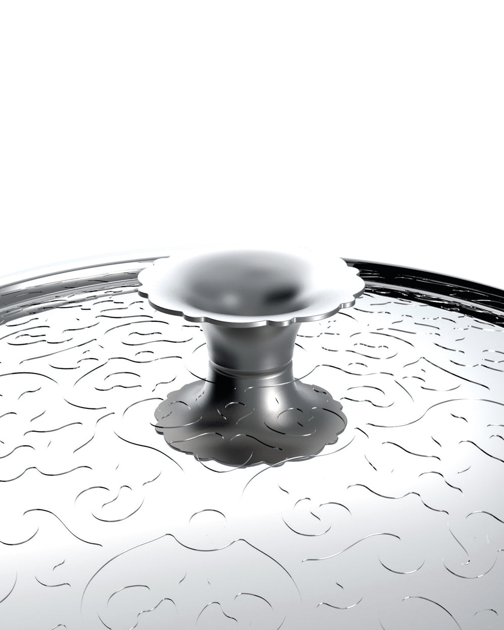 Silver metal pot lid by Alessi, featuring an etched wavy pattern and a scalloped handle.
