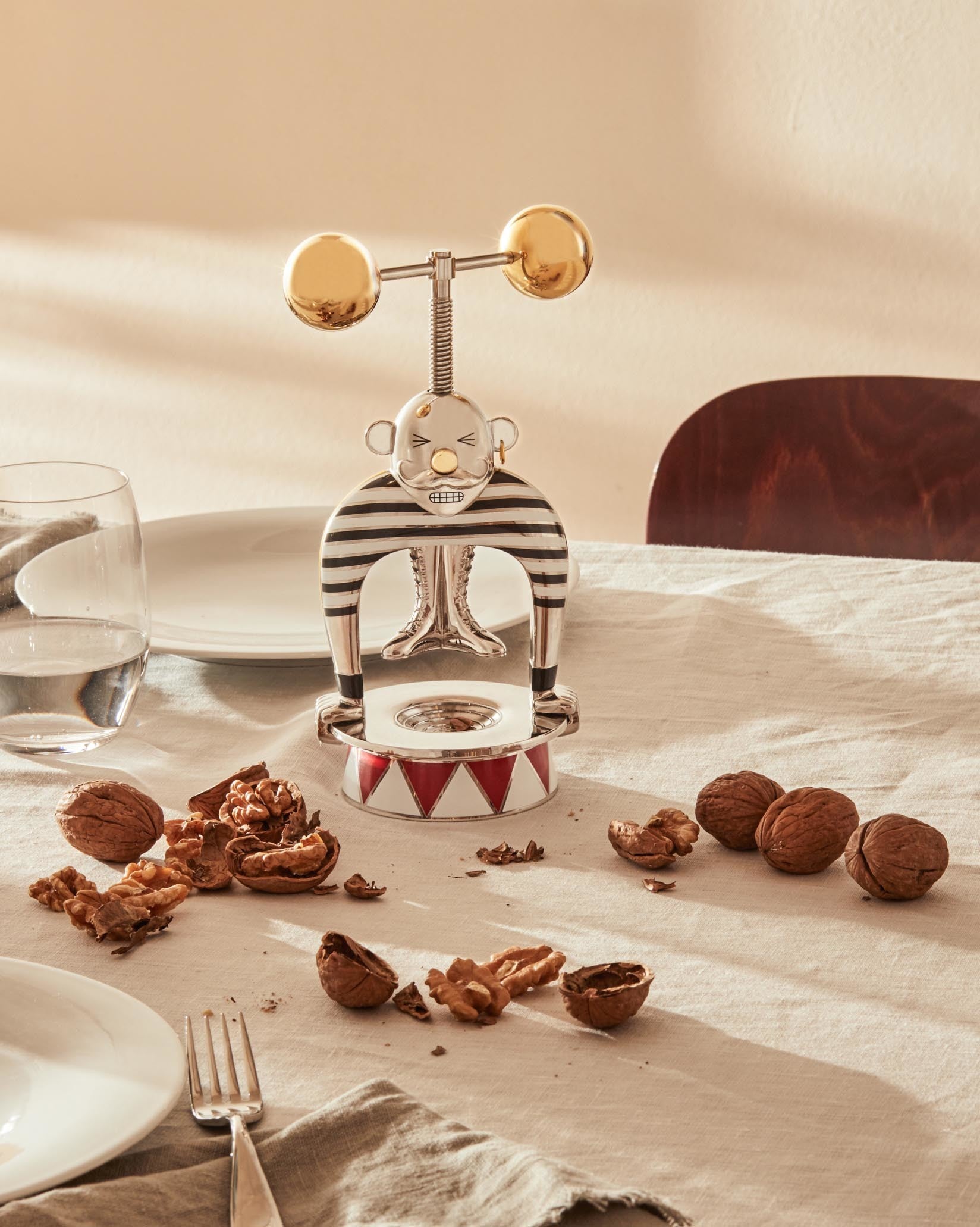 Silver and gold strongman nutcracker by Alessi, featuring a striped shirt, golden dumbbells, and a red and white circus tent base.