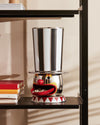 Clown-shaped candy dispenser by Alessi, featuring a black and white striped top hat and a red mouth filled with candies.