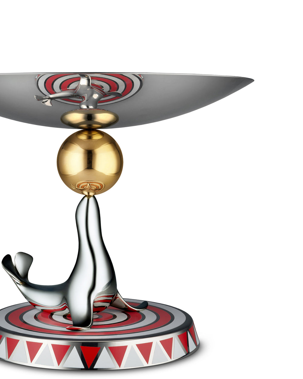 Polished silver seal figurine by Alessi, balancing a gold ball and supporting a sleek metal bowl on a red and white patterned base.