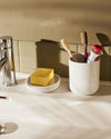 White Birillo by Alessi, a soap dish with a metal grate and a cylindrical toothbrush holder.