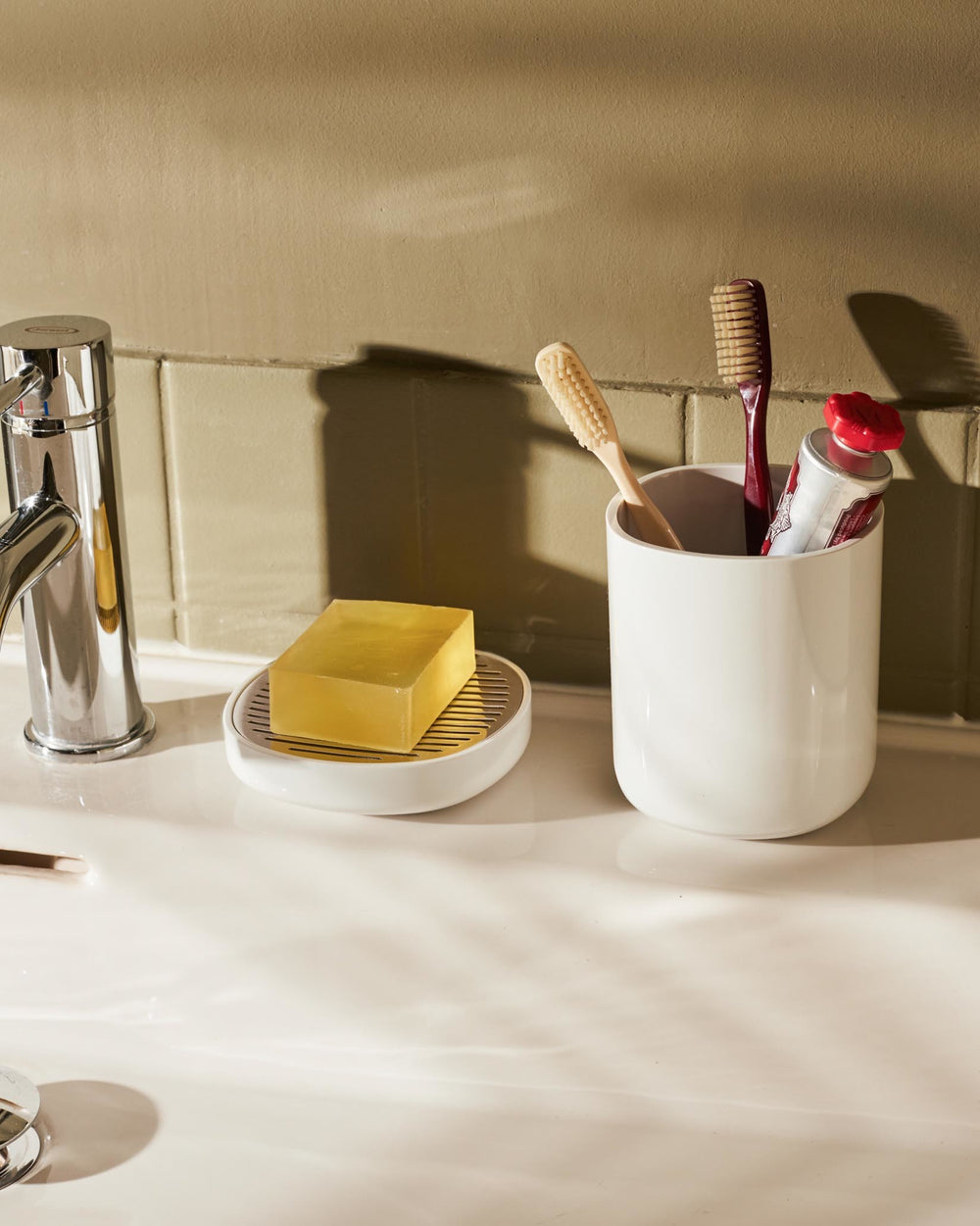 White Birillo by Alessi, a soap dish with a metal grate and a cylindrical toothbrush holder.