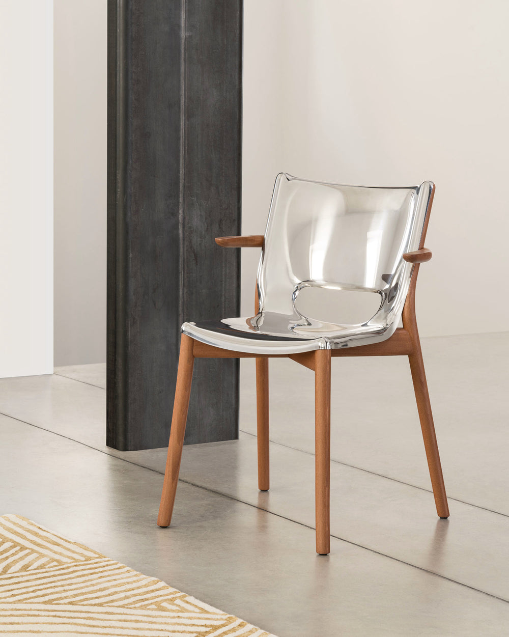 A modern chair with a clear acrylic seat and light wood frame by Alessi, featuring curved armrests and sleek tapered legs.