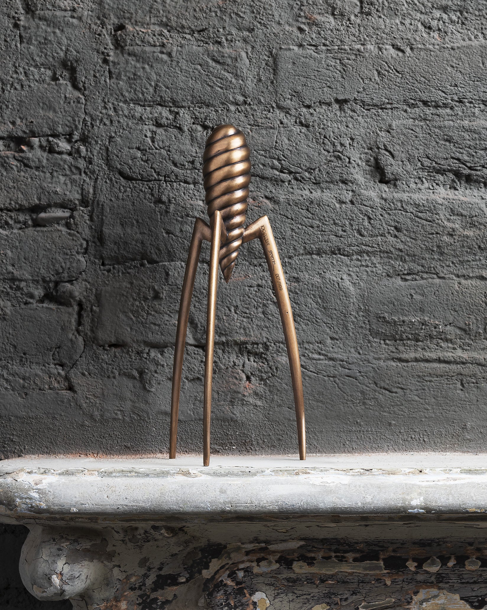 Bronze-toned sculptural lemon squeezer by Alessi, with a spiral body, three slender legs, and an etched edition number.