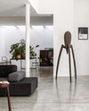 Large dark brown Juicy Salif XXL sculpture by Alessi, with three slender legs and ribbed top, in a modern minimalist interior.