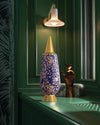 Multi-colored confetti patterned decorative item with gold accents by Alessi, standing on a dark green counter.