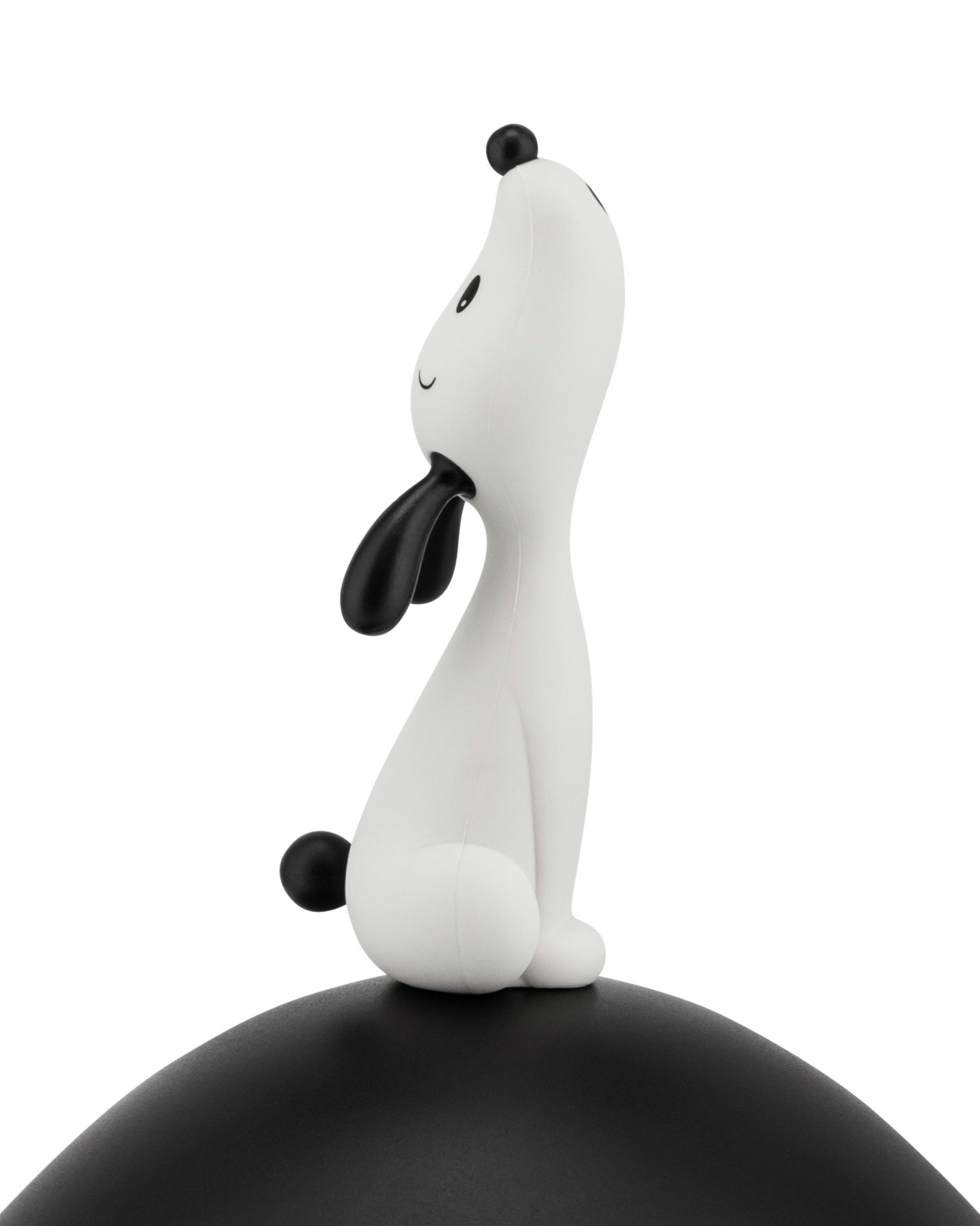 White and black stylized dog figure by Alessi, sitting with its head tilted up, on a curved black base.