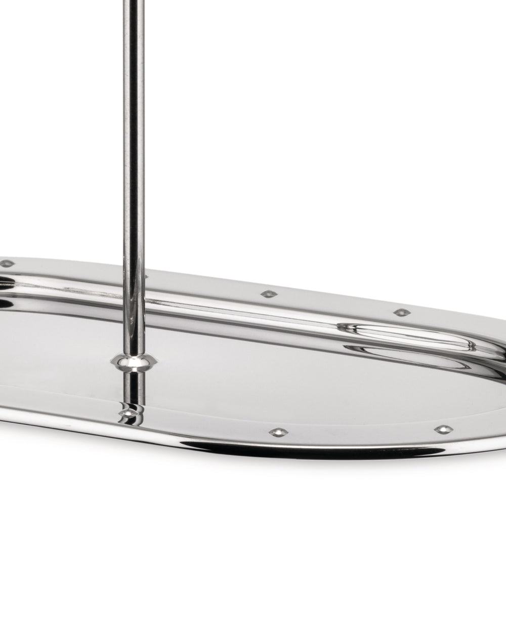Cropped view of a polished metal oblong serving tray by Alessi, with a central rod and decorative studs.