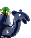 A navy blue decorative camel by Alessi with gold stars, a green and gold patterned hump, and a stylized closed eye.