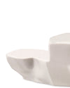 White sculptural serving dish by Alessi with an irregular, rock-like shape and glossy finish, cropped.