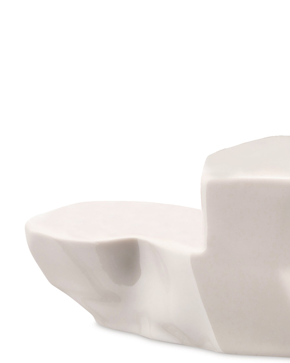 White sculptural serving dish by Alessi with an irregular, rock-like shape and glossy finish, cropped.