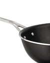 Black non-stick pan by Alessi with a polished silver handle and rim, shown in an angled close-up.